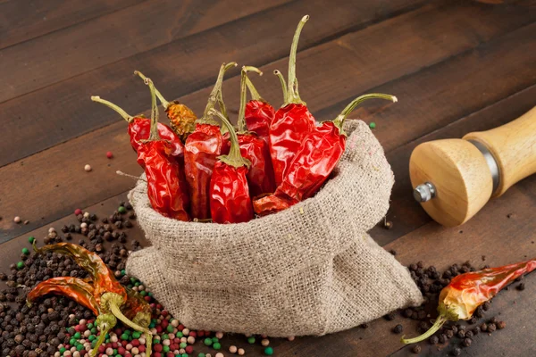 Red chili peppers in a canvas sack on wooden table — Stock Photo, Image