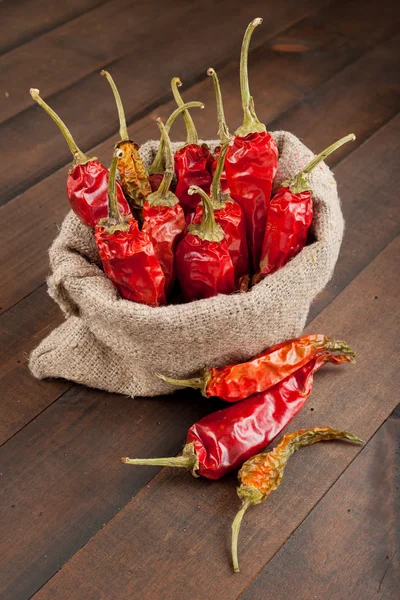 Red chili peppers in a canvas sack on wooden table — Stock Photo, Image