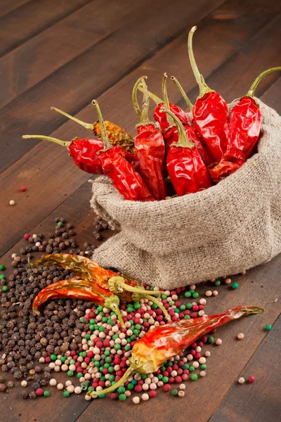 Czerwone papryki chili w płótnie worek na drewnianym stole — Zdjęcie stockowe