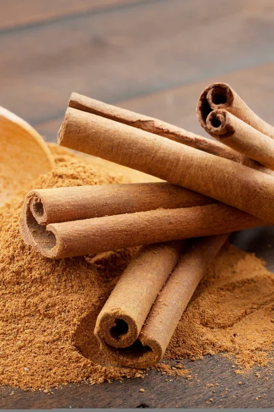 Cinnamon sticks and cinnamon powder in wooden scoop — Stock Photo, Image