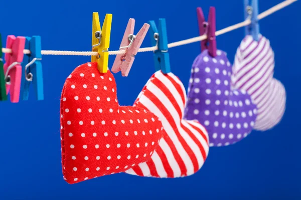 Herzen hängen an einer Wäscheleine mit Wäscheklammern, Fokus auf Rot. — Stockfoto