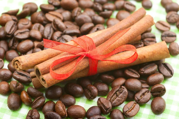 Cinnamon sticks with red ribbon on coffee beans — Stock Photo, Image
