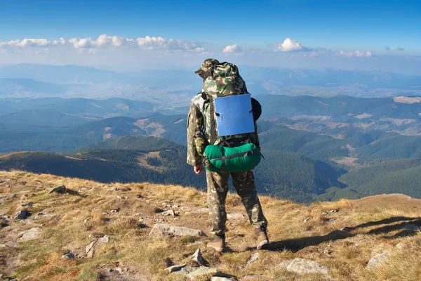 Caminhante masculino fica em um pico de montanhas e olhando o cenário — Fotografia de Stock