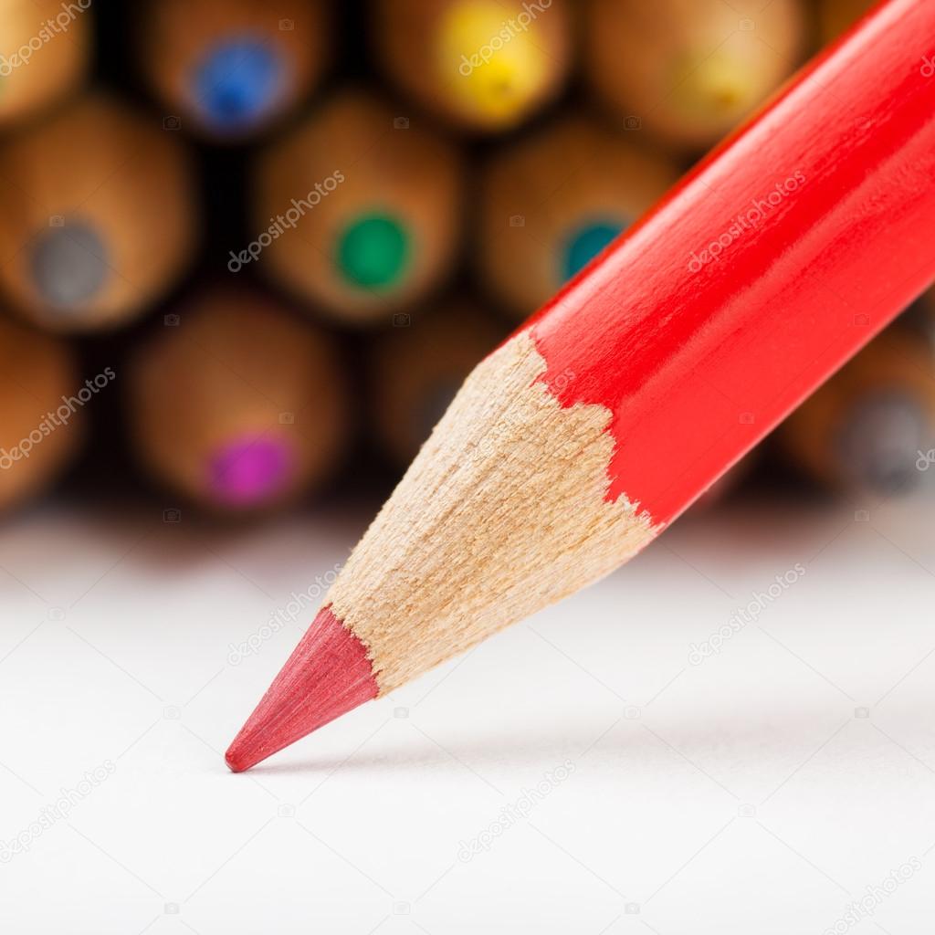red pencil draws or writing on paper sheet, colored pencils as b