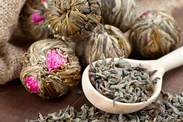 Groene thee ballen met bloemen en houten lepel op keukentafel — Stockfoto