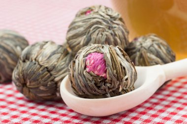 Green tea balls with flowers, tea cup and wooden spoon on kitche