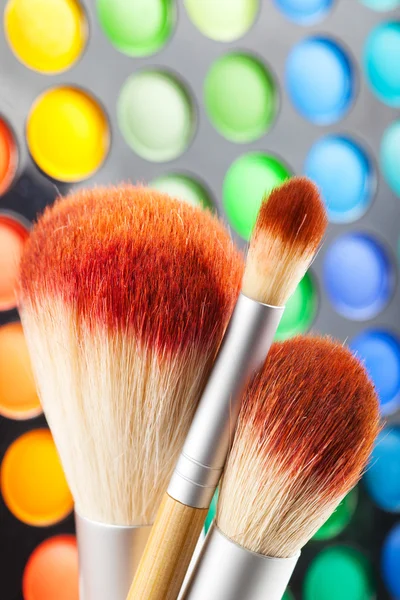 Makeup penslar och en uppsättning färgglada ögonskuggor som bakgrund — Stockfoto