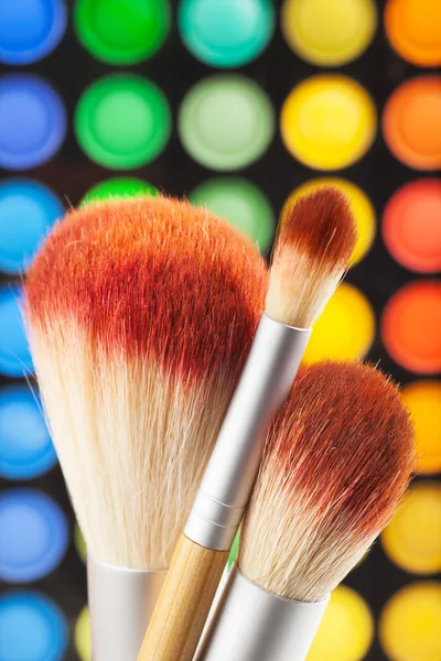 Pennelli trucco e set di ombretti colorati come sfondo — Foto Stock