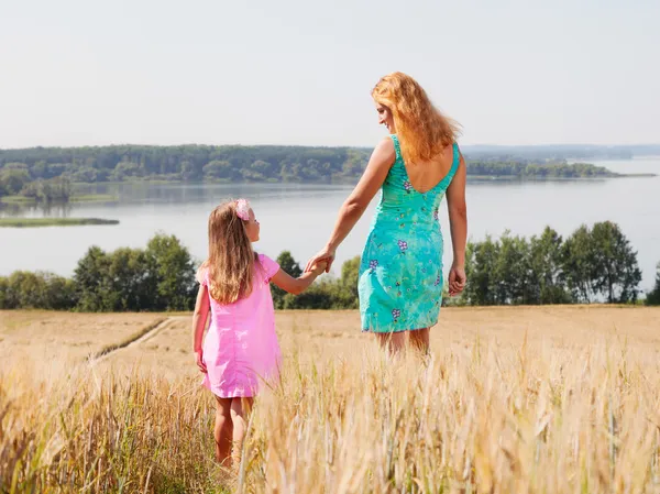 Mother and daughter walking in summer field — Stock Photo, Image