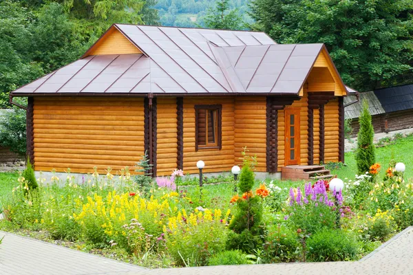 Casa de madera de pueblo con cama de flores —  Fotos de Stock
