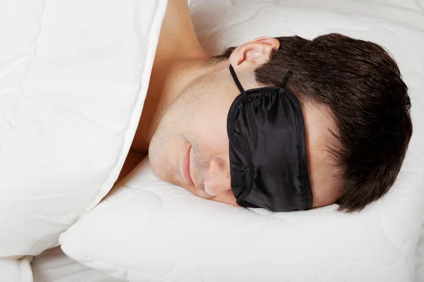 Hombre con máscara de dormir dormir acostado en la cama —  Fotos de Stock