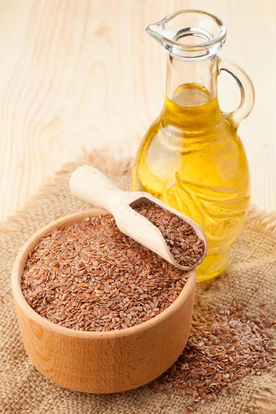Mortar of flax seeds with wooden scoop and linseed oil in glass — Stock Photo, Image