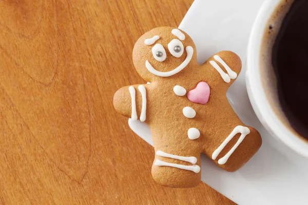 Lachende gingerbread man en koffie beker op tafel — Stockfoto