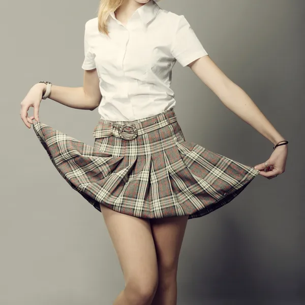 Young lady lifting up her short plaid skirt