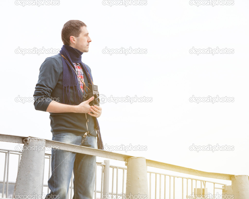Young man with vintage camera on a jetty