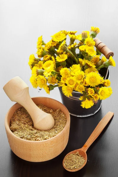 Mortero en la mesa y cubo con flores de pie de popa, hierbas medicinales — Foto de Stock