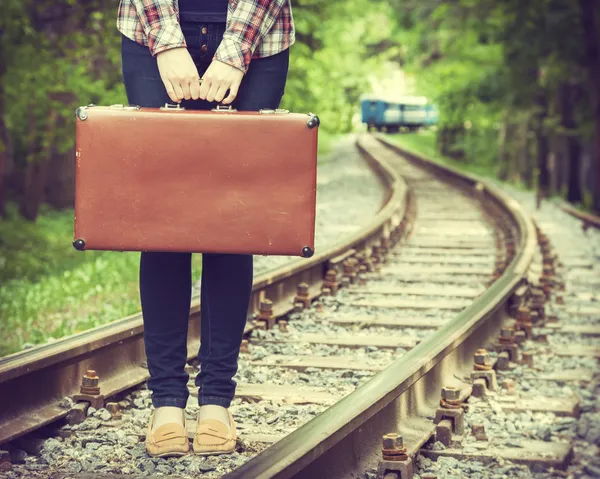 Giovane donna con vecchia valigia su ferrovia — Foto Stock