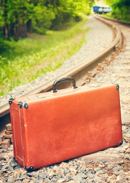 Valigia d'epoca sulla ferrovia, treno blu è spento — Foto Stock