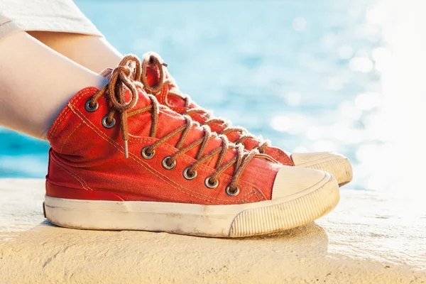 Zapatillas de deporte rojas en la chica y el paisaje marino como fondo — Foto de Stock