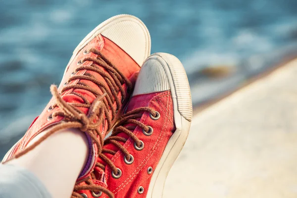 Scarpe da ginnastica rosse alla moda su ragazza e paesaggio marino come sfondo — Foto Stock