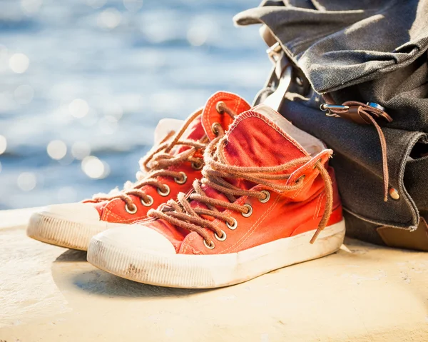 Sneakers och ryggsäck på seascape — Stockfoto