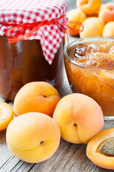 Rijpe abrikoos vruchten en jar van jam op tafel — Stockfoto