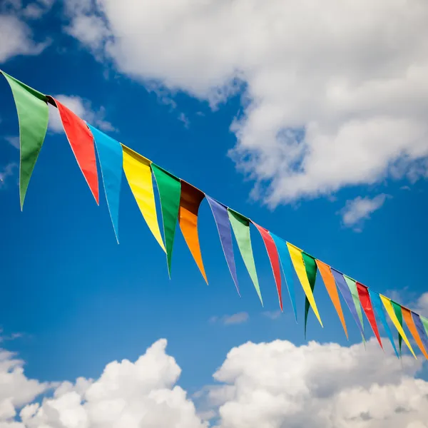 Multi-színes háromszög zászlók a kék ég háttér — Stock Fotó