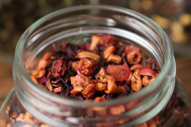 Aromatic natural fruit tea with hibiscus petals, fruit slices and berries. Closeup of dry organic fruit tea in an open glass jar for storing tea.