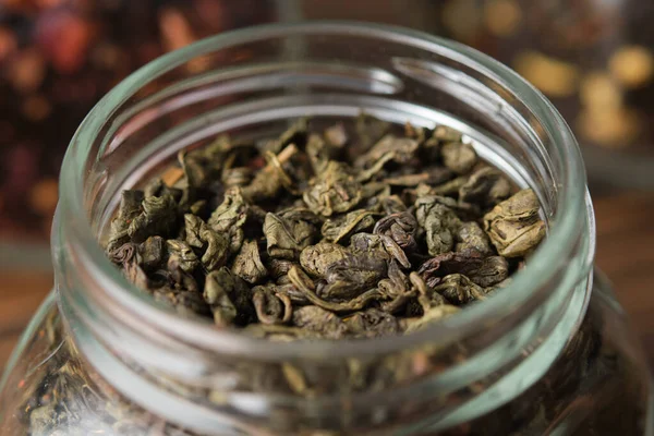 Green gunpowder tea. Dry green tea leaves in an open glass jar for storing tea.