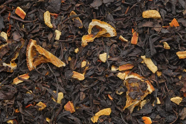 乾燥した柑橘類のスライスと皮を持つ芳香のある紅茶の葉の背景 ドライブラックティーの食感 — ストック写真