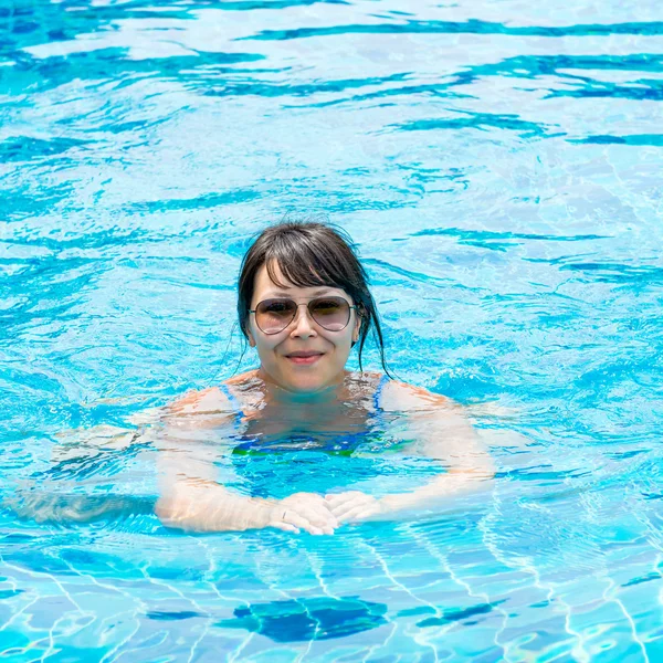 Portrait of a beautiful young girl in sunglasses floating in the — Stock Photo, Image