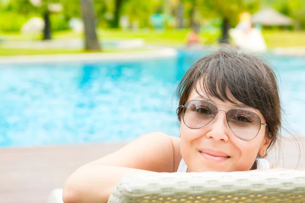 Portrait of a young beautiful woman with sunglasses lying on a s — Stock Photo, Image