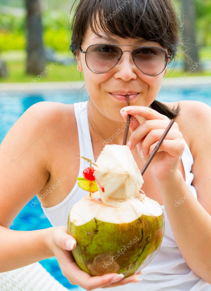Pretty woman drinking coconut cocktail against outdoor pool — Stock Photo © deduhin 46996755