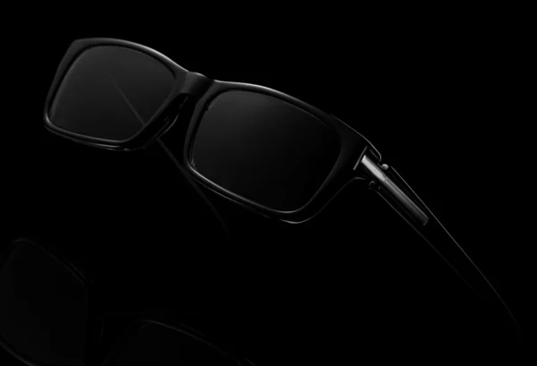 Black sunglasses isolated on black background — Stock Photo, Image