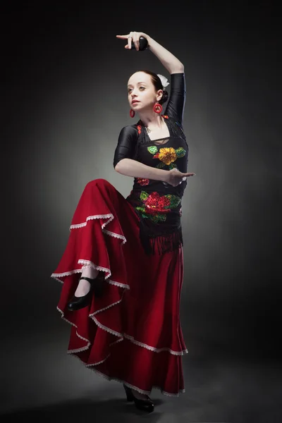 Mladá žena tančí flamenco s kastaněty na černém pozadí — Stock fotografie
