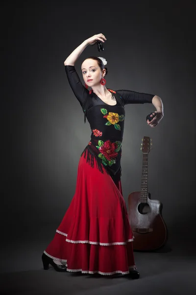 Ung kvinna dansar flamenco med kastanjetter på svart — Stockfoto