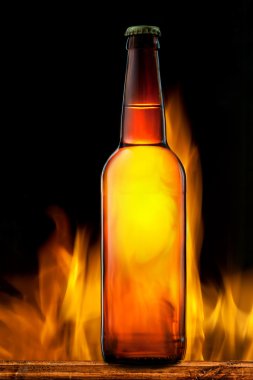 Beer bottle in fire on black clipart