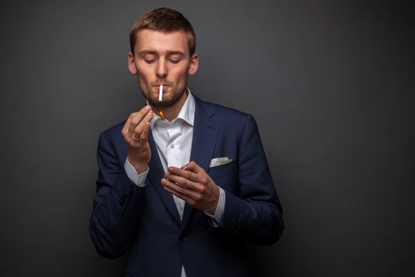 Portrét pohledný podnikatel s cigaretou na černém pozadí — Stock fotografie