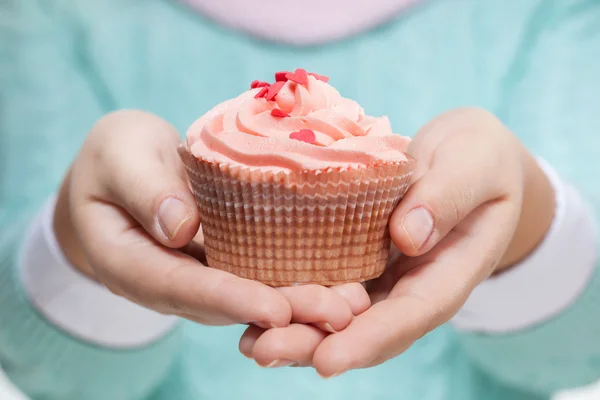 Mulher segurando um cupcake rosa no branco — Fotografia de Stock