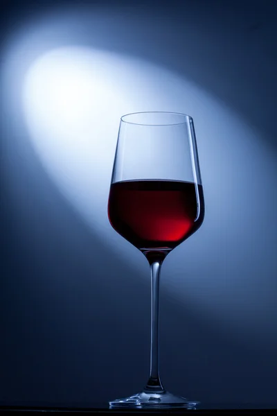 Красное вино в бокале на голубом — стоковое фото