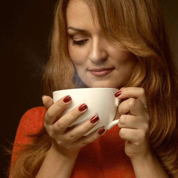 Женщина держит горячую чашку и улыбается — стоковое фото