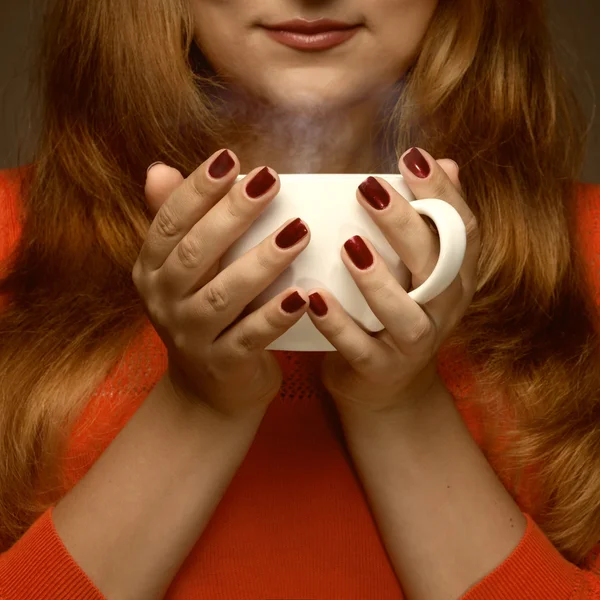 Mulher segurando copo quente e sorrisos — Fotografia de Stock