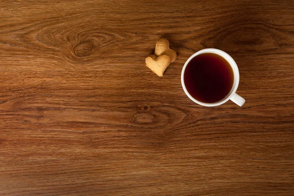 Varm kopp te med kakor på träbord — Stockfoto