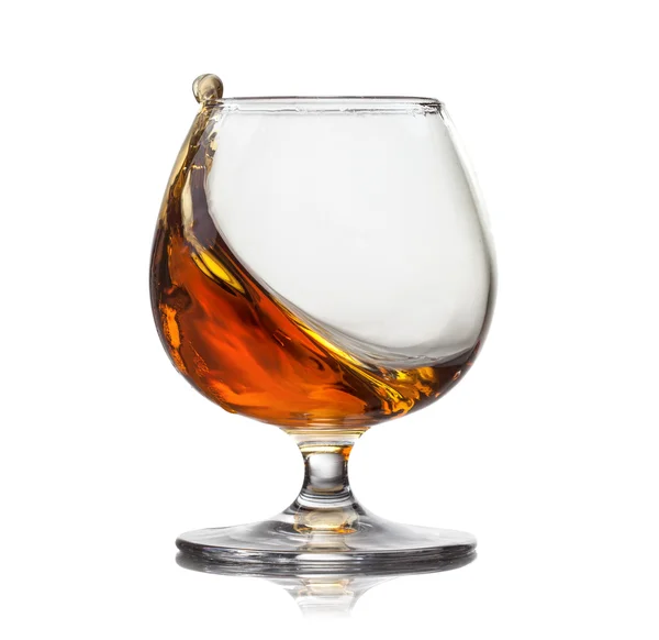 Splash van cognac in glas geïsoleerd op witte achtergrond — Stockfoto
