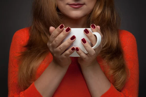 Woman holding hot cup and smiles — Stock Photo, Image
