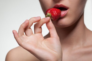 Young woman biting strawberry isolated on white