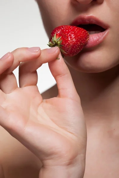 Young woman biting strawberry isolated on white — Stok fotoğraf