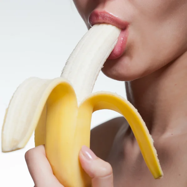 Young woman biting banana isolated on white — Stock Photo, Image