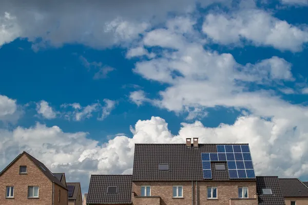 Nieuwe huizen met zonnepanelen op het dak onder de blauwe hemel en wolken — Stockfoto