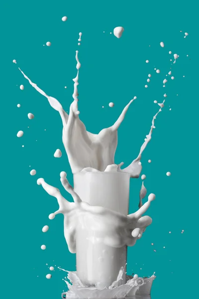 Milk splash in glass isolated on blue background — Stock Photo, Image